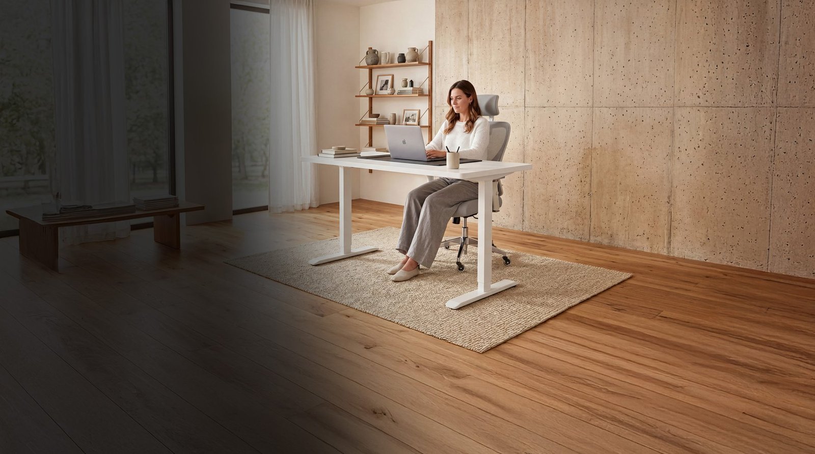 Frau arbeitet an einem höhenverstellbaren Schreibtisch auf einem ergonomischen CLOUVOU Bürostuhl